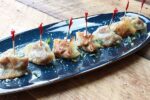 Butternut squash wontons on a long blue serving platter with toothpicks inserted into each wonton.