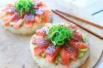 fresh sushi-grade tuna and salmon on top of avocado and round cakes made of sushi rice