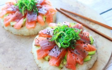 fresh sushi-grade tuna and salmon on top of avocado and round cakes made of sushi rice