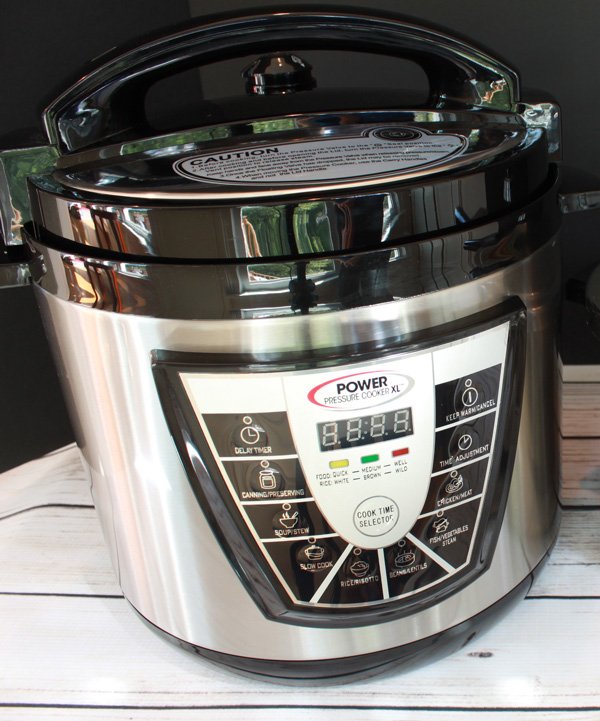 A Power Pressure Cooker XL on top of a white plank wooden board.