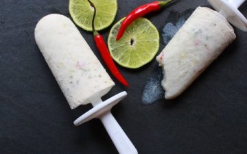 tropical coconut chili lime popsicles with lime slices and chili peppers