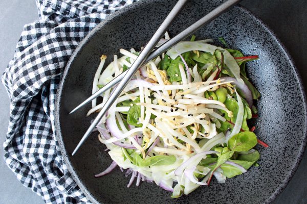 Spicy Kale and Fennel Salad with Lemon Vinaigrette in a grey bowl with chopsticks and a checkered napkin on the side.