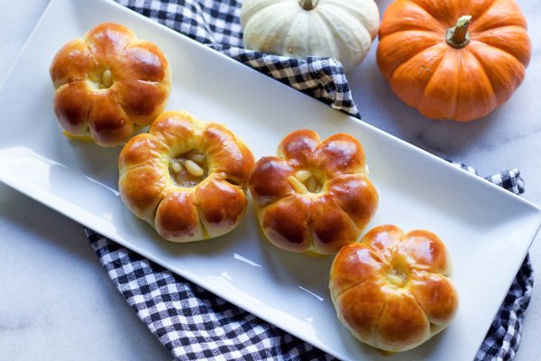Japanese pumpkin manju cookies on a white plate with a checkered napkin unerneath