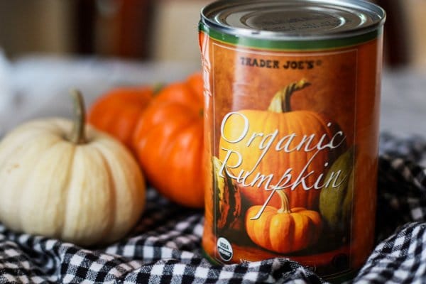a can of Trader Joe's organic pumpkin puree on a checkered napkin with baby pumpkins behind