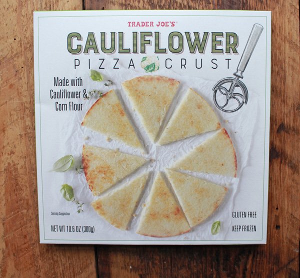 A box of Trader Joe's Cauliflower Pizza Crust on top of a wooden board.
