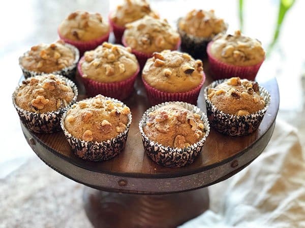 Banana nut muffins placed on a round wooden pedestal on top of a white napkin.