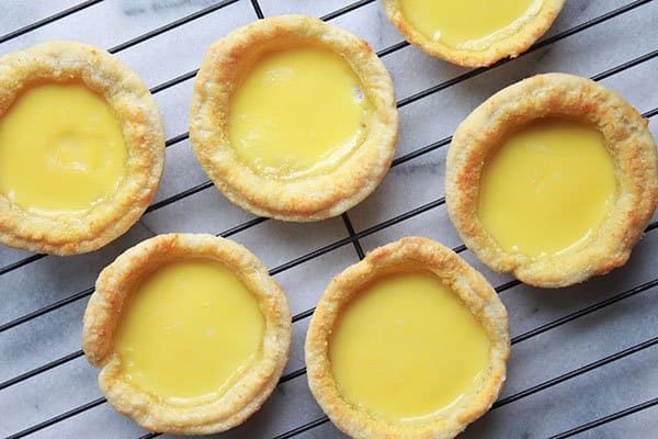 Chinese egg custard tarts in rows on a cooling rack.