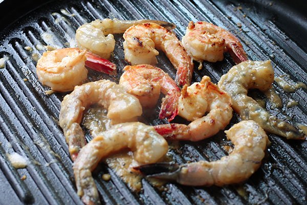 Shrimp being grilled on a grill pan.