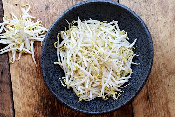 Asian bean sprouts in a black bowl on a wooden board