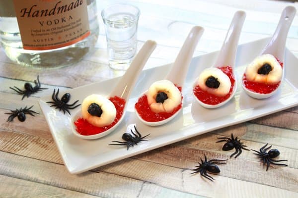 lychee jello shots in small white serving spoons on top of a white tray