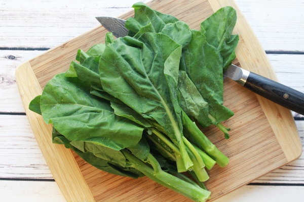 Chinese broccoli on a cutting board with chef's knife.