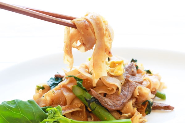Thai Pad See Ew stir fried noodles on a plate with chopsticks and Chinese broccoli