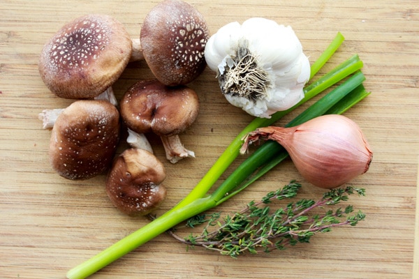 shiitake mushrooms, garlic, shallot, scallion, and thyme on board.