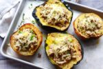 stuffed roasted acorn squash with ground turkey and rice on a baking tray.