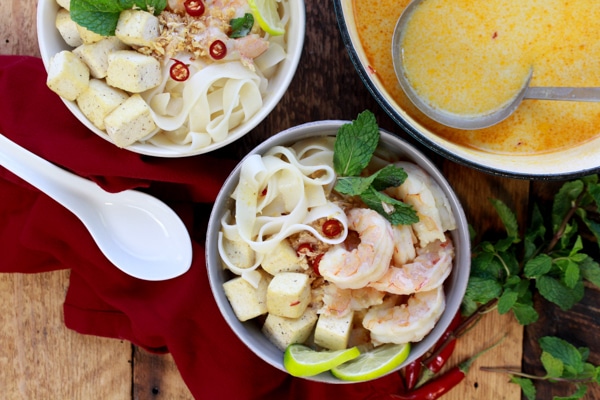 Singapore laksa with shrimp, tofu, and rice noodles in a bowl and in a Dutch oven with ladel