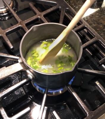 stirring ingredients for simple syrup in a small saucepan on a stovetop