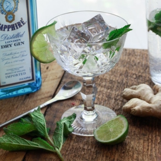 minty gin fizz cocktail in a crystal glass with a lime slice and bottle of Sapphire gin