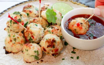 spicy baked shrimp balls on a round white plate being dipped in a sweet chili sauce