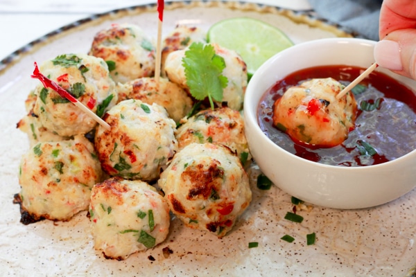 spicy baked shrimp balls on a round white plate being dipped in a sweet chili sauce