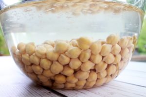 chickpeas soaking in water in a glass bowl