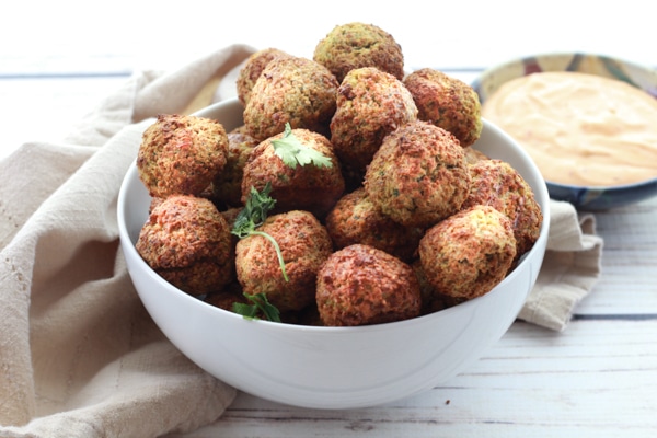 air-fried falafel balls in a white bowl with a side of spicy aioli dipping sauce