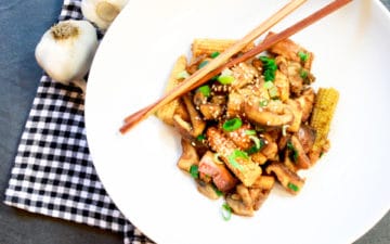 shiitake mushrooms and baby corn on a white plate with chopsticks