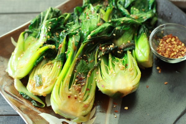 stir-fried baby bok choy on a serving plate sprinkled with red pepper flakes