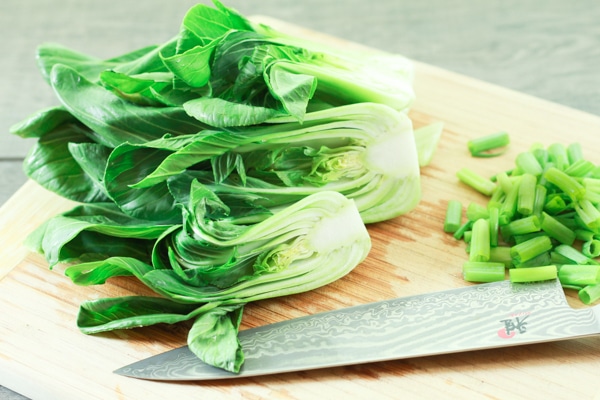 baby bok choy on a cutting board with a knife