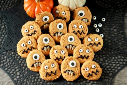 pumpkin monster cookies on a black place mat with baby pumpkins