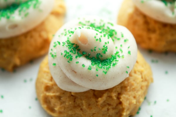 a pumpkin spice cookie topped with cream cheese frosting and green sprinkles