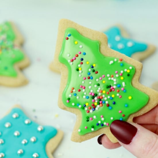 woman holding up a glazed and decorated Christmas cookie