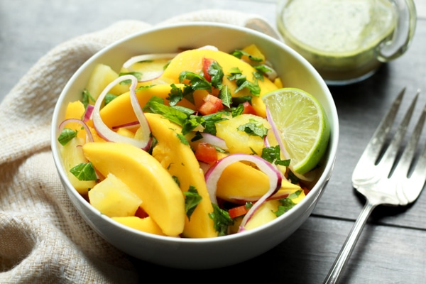 vibrant mango and pineapple salad in white bowls with a silver fork