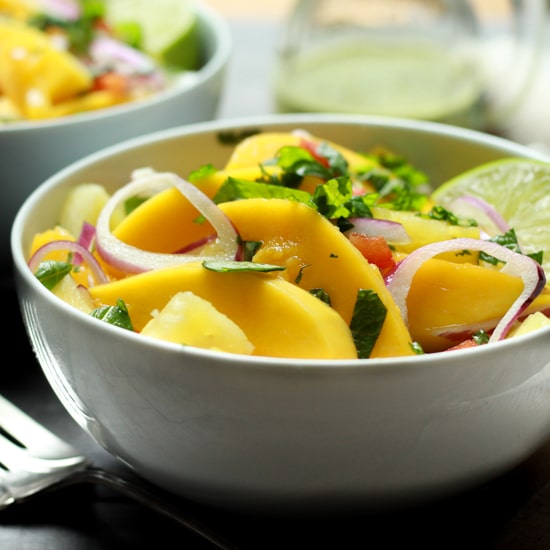 vibrant mango and pineapple salad in white bowls with lime vinaigrette on the side