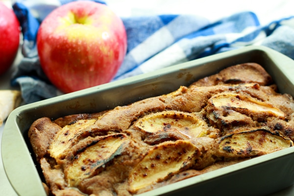 apple ginger bread in a loaf pan with red apples in the background