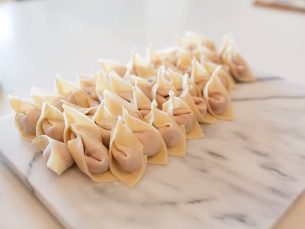 stacks of fresh, stuffed wontons on a marble board