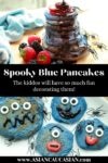 a stack of blue pancakes with black syrup dripping down the stack with vibrant berries and decorated blue monster pancakes on a white plate