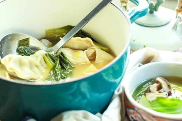 a blue stock pot filled with wonton soup and a smaller bowl on the side