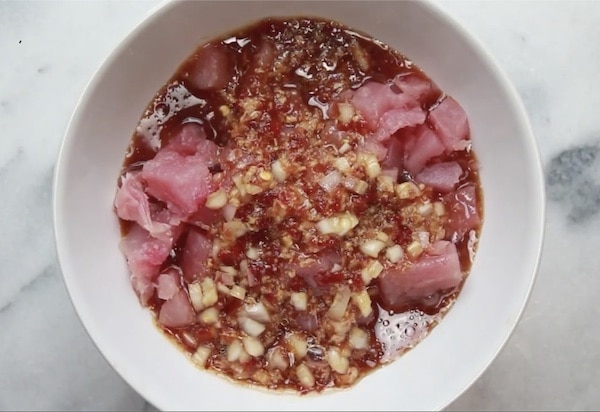 A white bowl filled with chopped Ahi tuna in an Asian marinade.