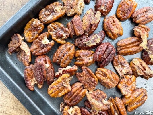 Golden, toasted spiced pecans on a baking tray.