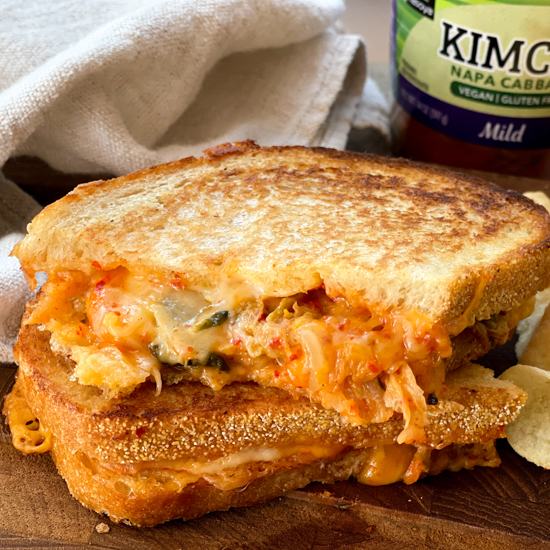 a stacked kimchi grilled cheese sandwich on a wooden board