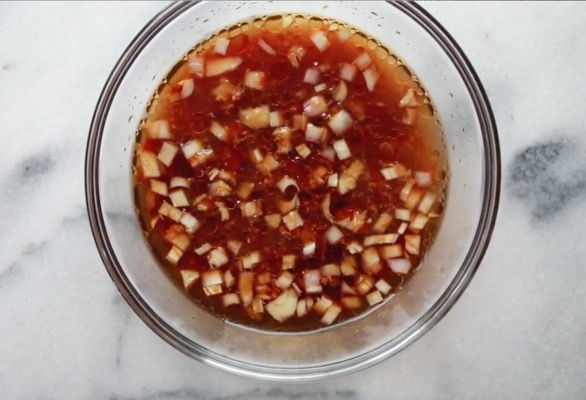 A clear glass bowl filled with a brown Asian sauce.