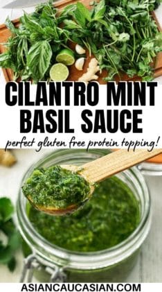 A clear glass jar of cilantro, mint, basil sauce with a small wooden spoon inserted, and bunch of fresh cilantro and basil leaves, and ginger root.