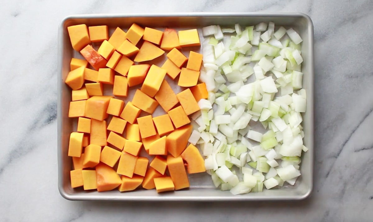 Cubed butternut squash and chopped onions on a baking tray