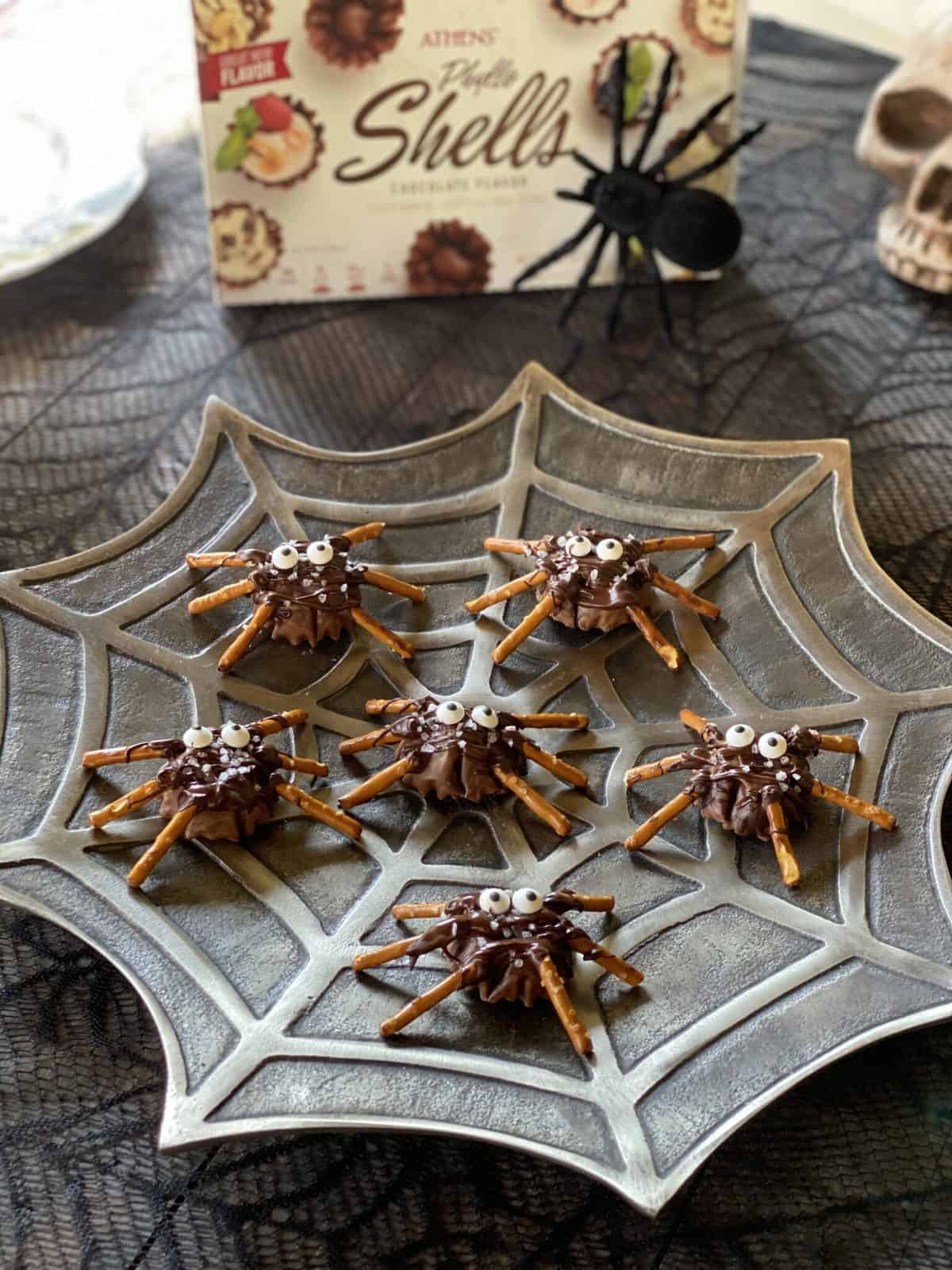 Spooky chocolate pretzel spiders for Halloween on a spider web serving platter.