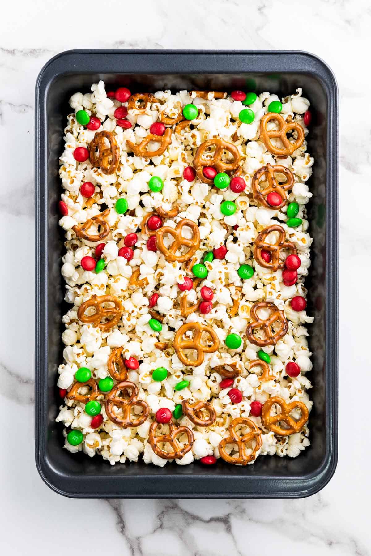 Christmas popcorn Santa munch in a black baking tray on top of a marble surface.