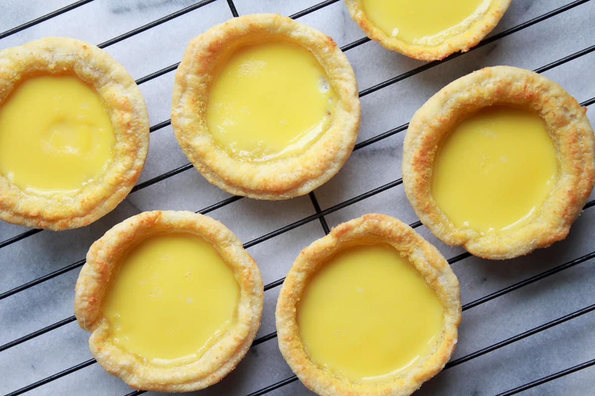 Rows of Chinese egg tarts cooling on a baking rack.