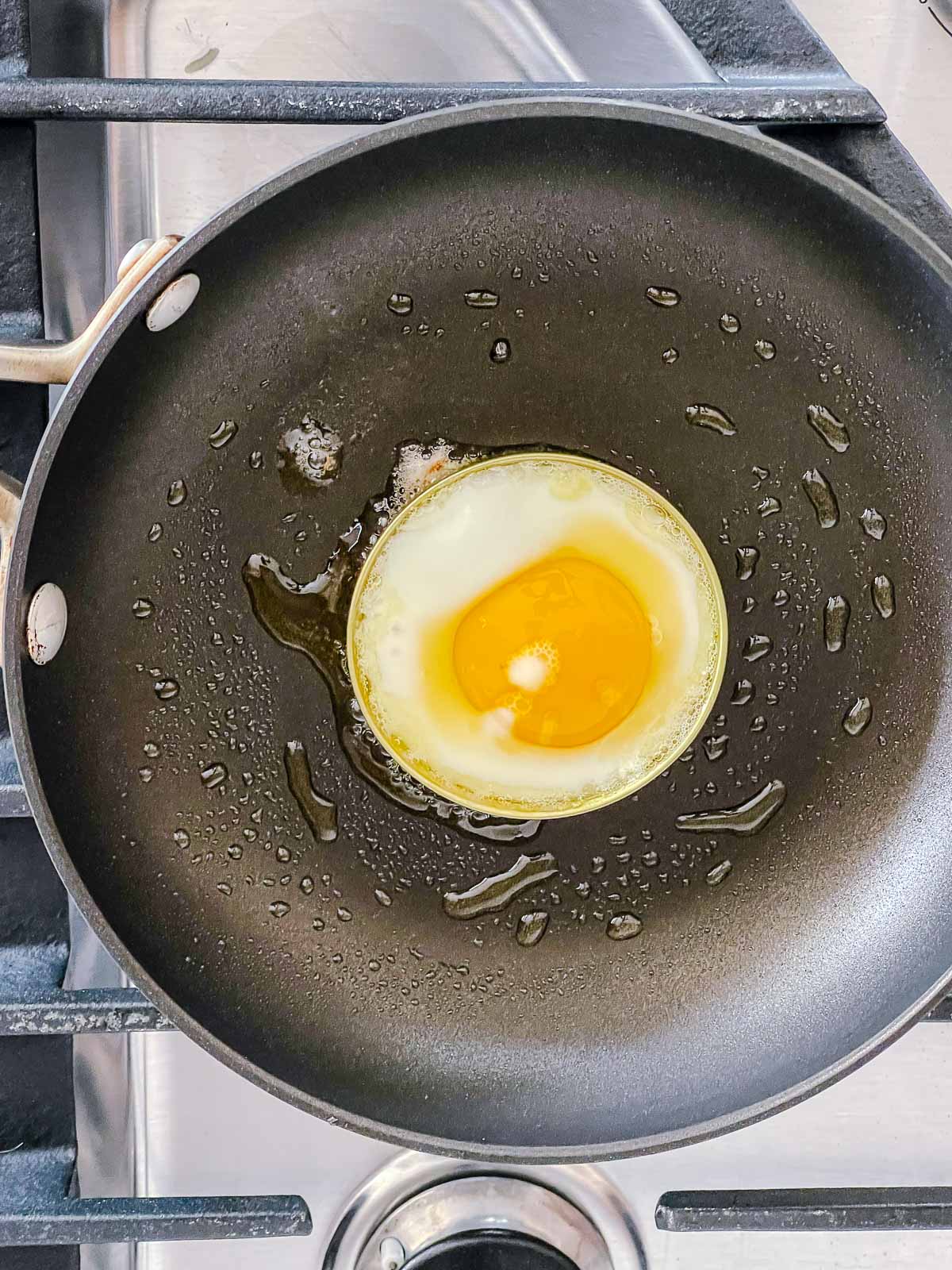A round runny egg cooked in a frying pan on top of a stove.