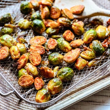 Air fryer brussels sprouts with gochujang in a silver basket right out of the air fryer.